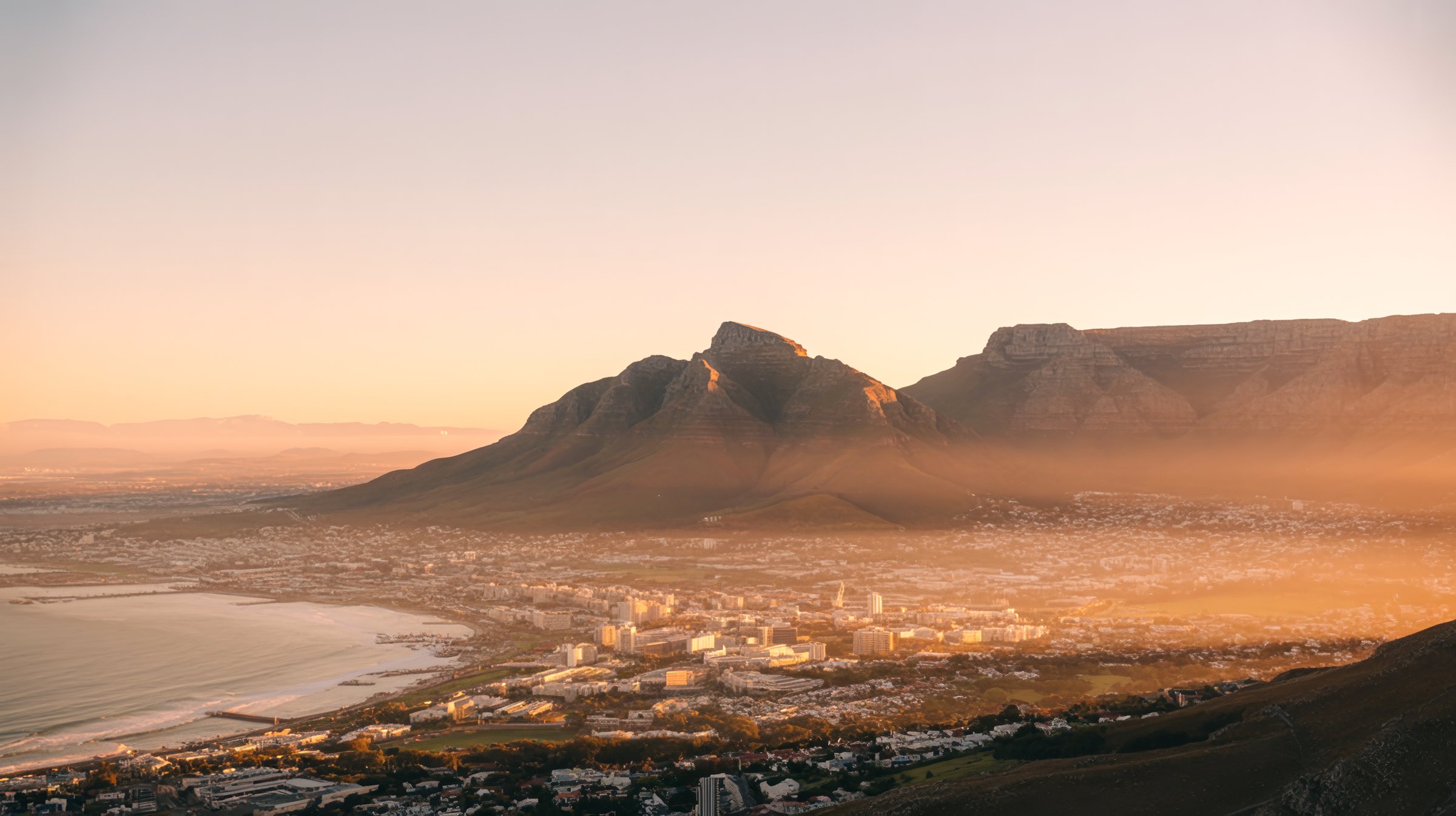 Cape Town at golden hour, Table Mountain rising on the horizon, the city below bathed in warm light